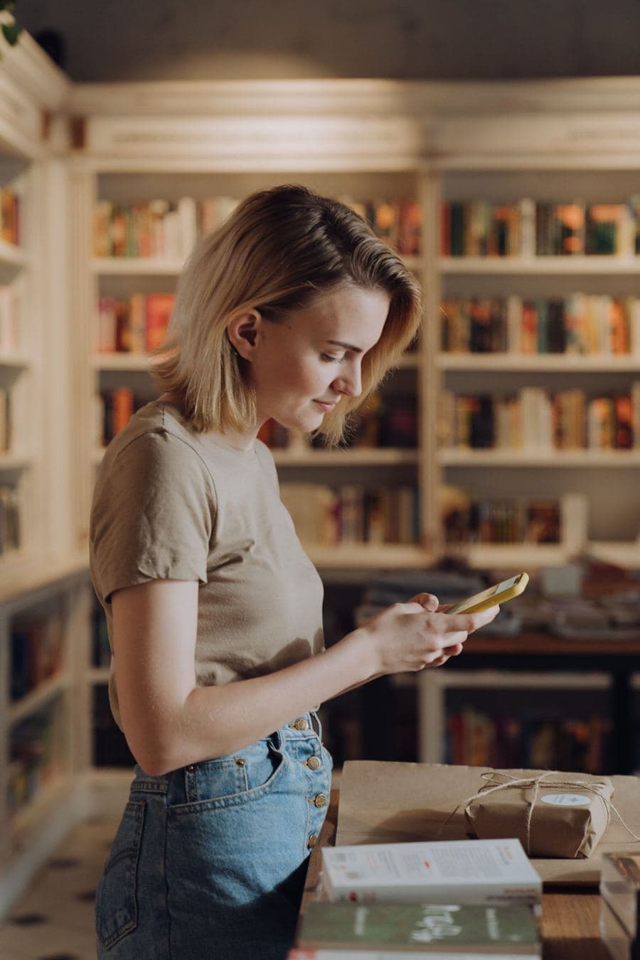 Woman reading her phone in a bookshop